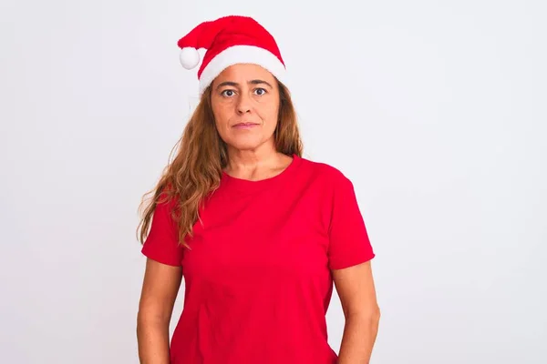 孤立した背景の上にクリスマスの帽子をかぶっている中年の成熟した女性顔に深刻な表情でリラックスしてください シンプルで自然なカメラを見て — ストック写真