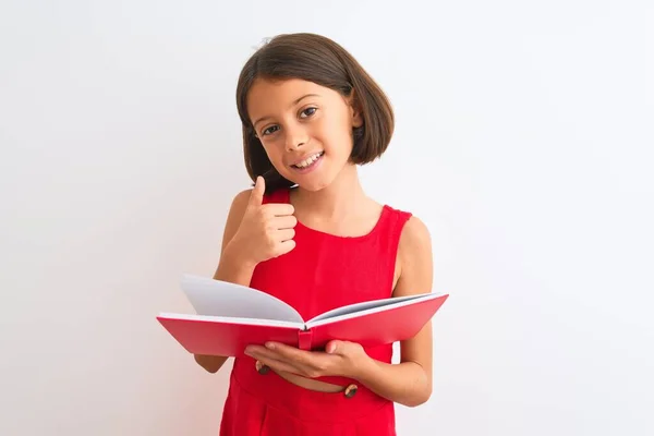 美しい学生子供女の子読書赤本立って上の隔離された白い背景幸せなで大きな笑顔を行いますOkサイン 親指アップとともに指 優れたサイン — ストック写真