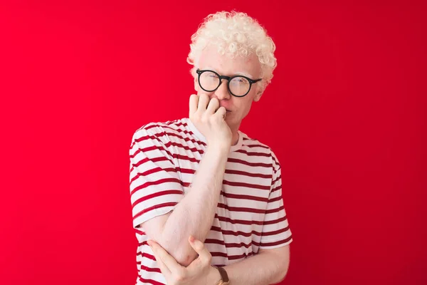 Młody Blondyn Albinos Pasiastej Koszulce Okularach Czerwonym Tle Wygląda Zestresowanego — Zdjęcie stockowe