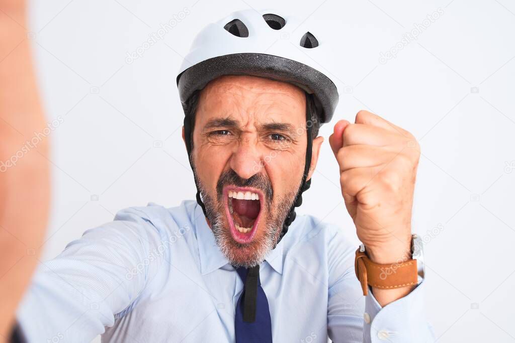 Middle age businessman wearing bike helmet make selfie over isolated white background annoyed and frustrated shouting with anger, crazy and yelling with raised hand, anger concept