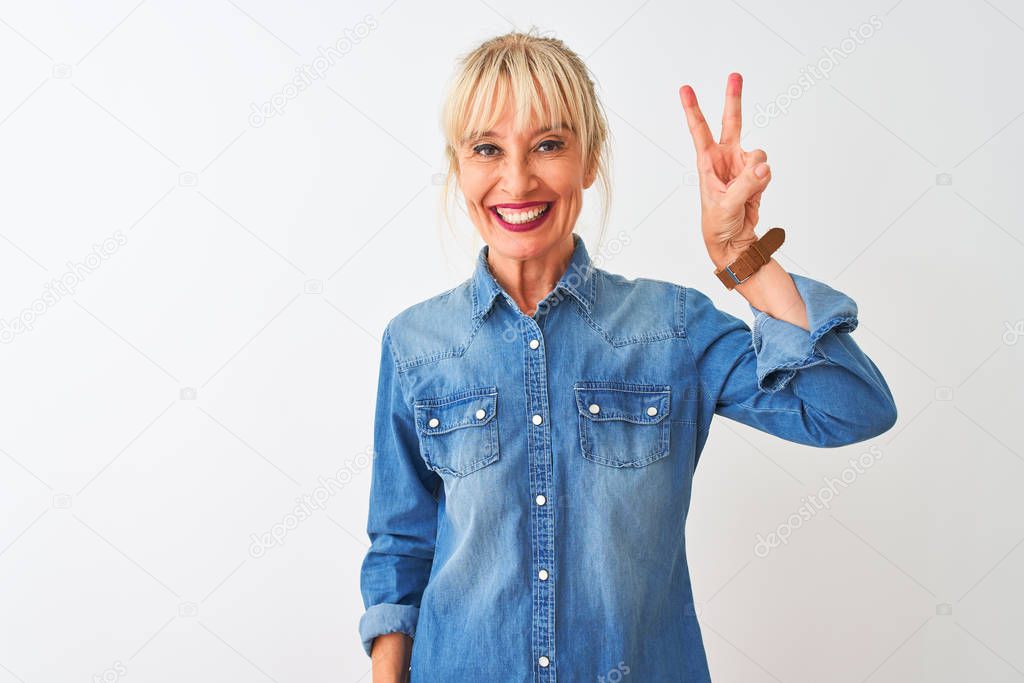 Middle age woman wearing casual denim shirt standing over isolated white background showing and pointing up with fingers number two while smiling confident and happy.