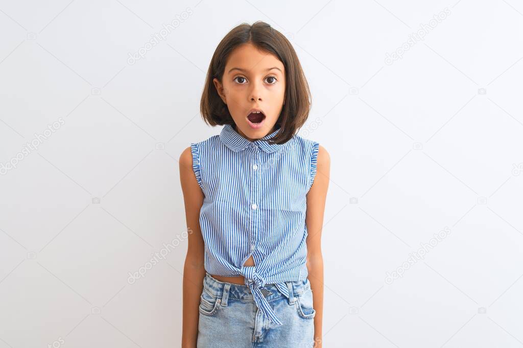 Young beautiful child girl wearing blue casual shirt standing over isolated white background afraid and shocked with surprise expression, fear and excited face.