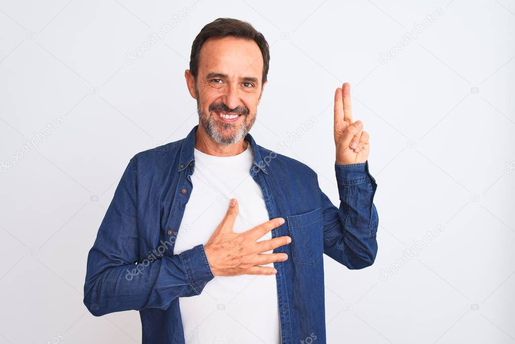 Middle age handsome man wearing blue denim shirt standing over isolated white background smiling swearing with hand on chest and fingers up, making a loyalty promise oath