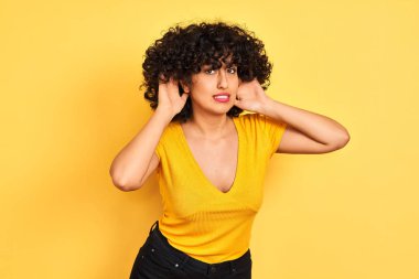 Sarı arka planda duran kıvırcık tişörtlü, kıvırcık saçlı genç Arap kadın iki elini de kulak hareketi yaparken duymaya çalışıyor, dedikoduya meraklı. İşitme problemi, sağır