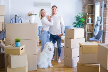 Karton kutular etrafında yeni evde duran köpek ile genç güzel çift