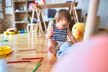 Anaokulunda bir sürü oyuncakla oynayan sevimli bir çocuk.