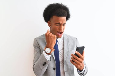 Genç Afrikalı Amerikalı iş adamı, izole edilmiş beyaz arka plan üzerinden akıllı telefon kullanıyor. Sinirli ve sinirli bir şekilde bağırıyor, çıldırıyor ve el kaldırarak bağırıyor. Öfke kavramı.