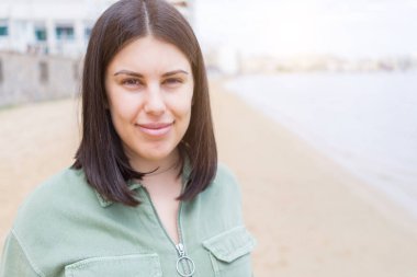 Genç güzel kadın plajda çok mutlu gülümseyen