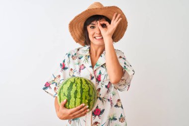 Yaz şapkası takan bir kadın izole edilmiş beyaz arka planda karpuz tutuyor. Gülümsüyor. Tamam işaret veriyor.