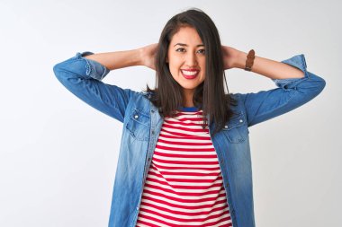İzole edilmiş beyaz arka plan üzerine çizgili tişört ve kot giyen genç Çinli kadın rahatlıyor ve esniyor, kolları ve elleri başının arkasında ve boynunun arkasında mutlu bir şekilde gülümsüyor.