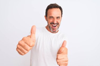 İzole edilmiş beyaz arka plan üzerinde dikilen orta yaşlı yakışıklı bir adam elinle olumlu jest yapmayı onaylıyor, gülümsüyor ve başarı için mutlu. Kazanan jest.