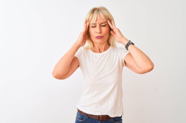 Orta yaşlı bir kadın, izole edilmiş beyaz arka planda duran ve stresten dolayı baş ağrısı çeken sıradan bir tişört giyiyor. Migren ağrısı..
