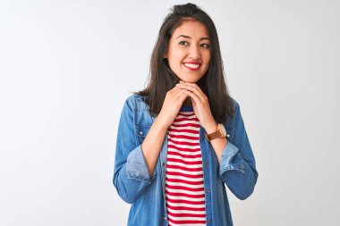 İzole edilmiş beyaz arka planda çizgili t-shirt ve kot gömlek giyen genç Çinli bir kadın gergin ve heyecanlı bir şekilde çenesinin kenarına bakıyor.