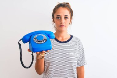 Genç kızıl saçlı kadın klasik retro telefonu izole edilmiş arka planda tutuyordu. Akıllı bir yüz ifadesiyle ciddi olduğunu düşünüyordu.