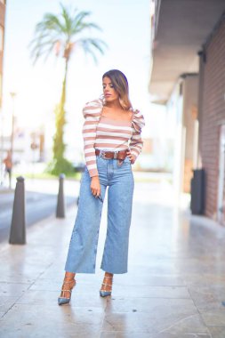 Mutlu ve kendinden emin gülümseyen genç ve güzel bir kadın. Şehir caddesinde ayakta ve yürüyorum.