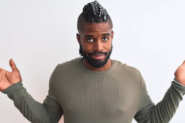 Yeşil süveter giyen Afrika kökenli Amerikalı bir adam izole edilmiş beyaz arka plan hakkında hiçbir şey bilmiyor ve elleri ve kolları havada şaşkın bir ifade sergiliyor. Şüphe kavramı.