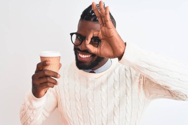 Örgü ören Afrikalı Amerikalı adam kahveyi izole edilmiş beyaz arka planda, gülümseyen yüzüyle kaldırıyor.