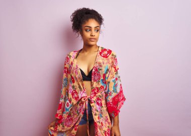 Genç güzel afro-amerikan kadın bikini ve renkli kaftan giyen ayakta tatilde