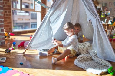 Anaokulunda bir sürü oyuncağın etrafında oynayan sevimli sarışın ikizler.