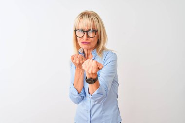 Orta yaşlı iş kadını zarif gömlek ve gözlük takıyor, beyaz arka planda. Yumruk savunma hareketleriyle dövüşmeye hazır, kızgın ve üzgün yüzlü, sorundan korkan.