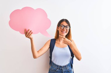 Güzel, kızıl saçlı, sırt çantası takan ve elinde konuşma balonuyla elini ve parmağını göstererek mutlu olan bir kız öğrenci.