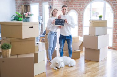 Karton kutuların etrafındaki yeni evlerinde ellerinde karatahtayla bekleyen genç ve güzel bir çift.