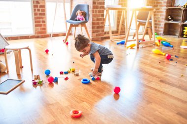 Anaokulunda tahta bloklarla tren inşaatıyla oynayan güzel bir çocuk.