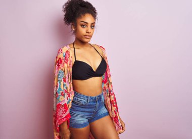 Genç güzel afro-amerikan kadın bikini ve renkli kaftan giyen ayakta tatilde