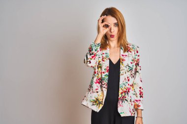 İzole edilmiş arka planda bahar çiçeği ceketi giyen Kafkasyalı genç bir iş kadını şaşırmış yüz ifadesiyle şaşırmış, parmaklarından bakan bir jest yapıyor. İnançsız ifade.