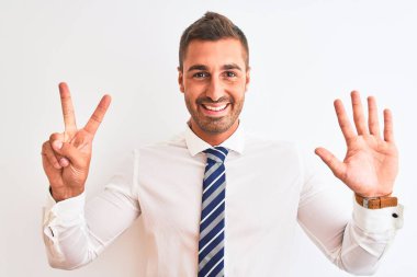Genç yakışıklı, zarif iş adamı izole edilmiş arka planda 7 numarayı gösterip işaret ederken kendine güvenen ve mutlu bir şekilde gülümsüyor..