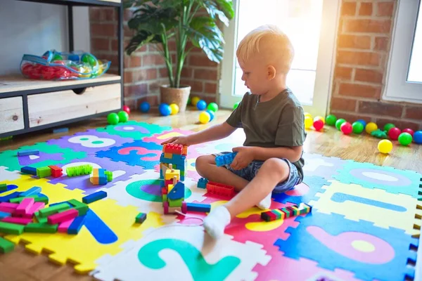 年轻的高加索小孩在幼儿园玩玩具块 学龄前男孩很高兴在游戏室建了一座塔 — 图库照片
