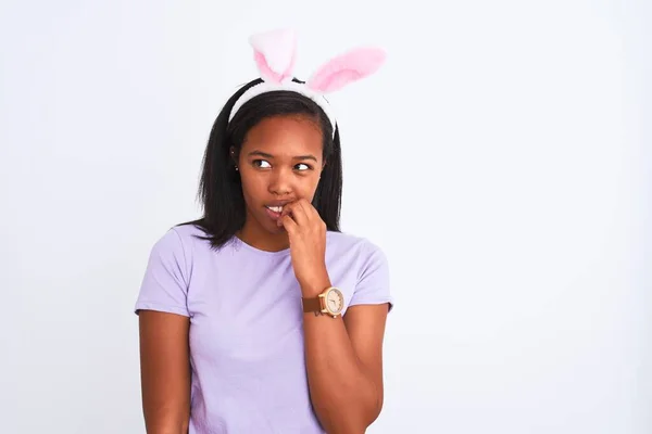 年轻的非洲裔美国女人戴着东部兔子耳朵 背景孤立 看起来紧张而紧张 双手放在咬指甲的嘴上 焦虑问题 — 图库照片