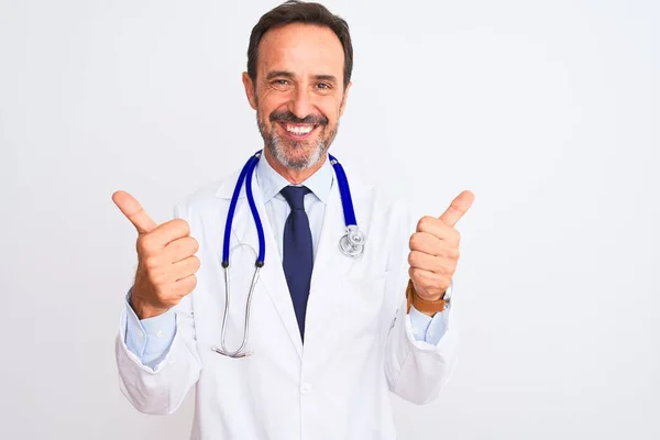 中年男人穿着外套和听诊器站在孤立的白色背景的成功标志上用手做着积极的手势 竖起大拇指微笑着 快乐地 快乐的表情和胜利的姿态 — 图库照片