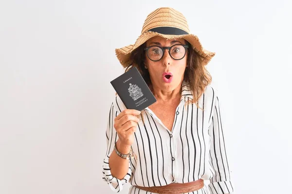 カナダのパスポートを持っているシニア観光客の女性は 驚きの顔でショックで怖がって孤立した白い背景の上に 恐怖表現で恐れて興奮しています — ストック写真