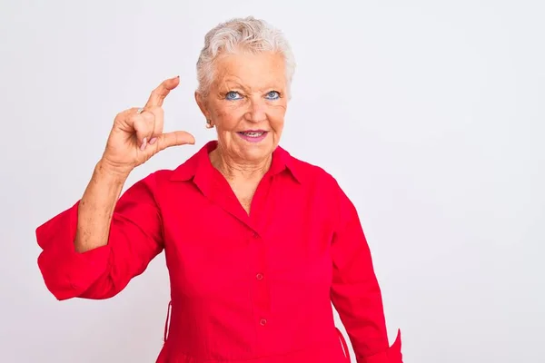 高个子灰发女人穿着红色休闲装 站在孤立的白色背景上 微笑着 自信地做手势 手拿着小尺寸的标志 手拿着手指 手拿着相机 计量概念 — 图库照片