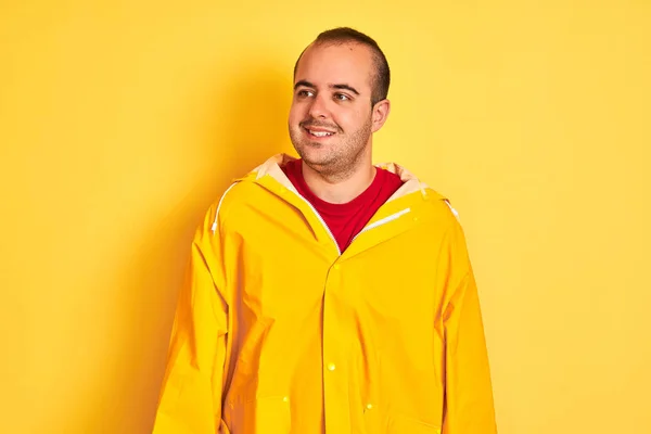 Νεαρός Άνδρας Φορώντας Αδιάβροχο Στέκεται Πάνω Από Απομονωμένο Κίτρινο Φόντο — Φωτογραφία Αρχείου