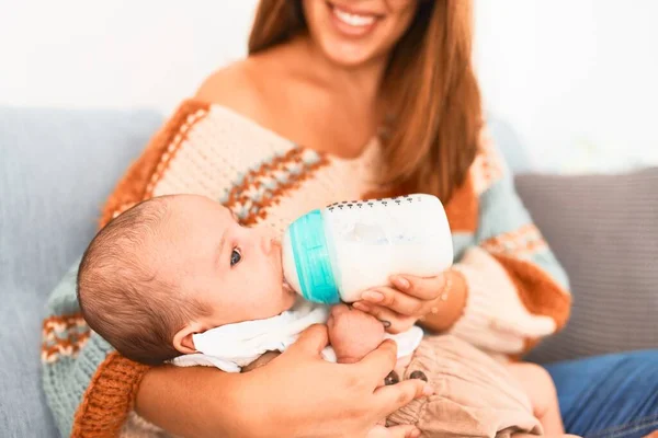 若い美しい女性と自宅でソファの上で彼女の赤ちゃん 新生児と母親は 哺乳瓶を使用して快適な飲料牛乳をリラックスして休憩 — ストック写真