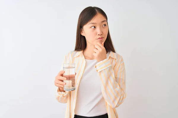 年轻的中国女人戴着眼镜 在与世隔绝的白色背景下喝着一杯水 严肃地思考着问题 非常迷惑的想法 — 图库照片