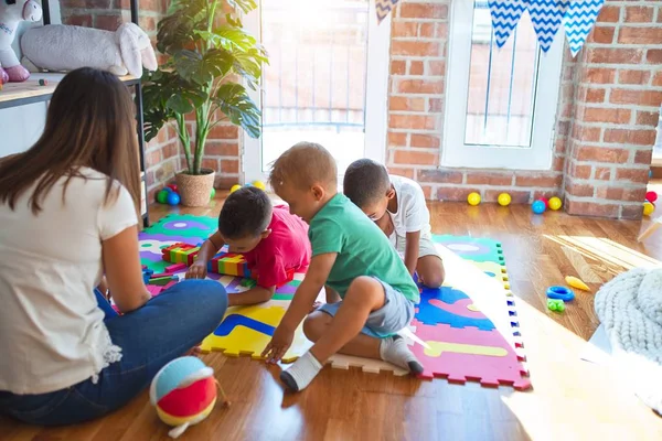 在幼儿园里 年轻漂亮的老师和蹒跚学步的孩子们在玩很多玩具 — 图库照片