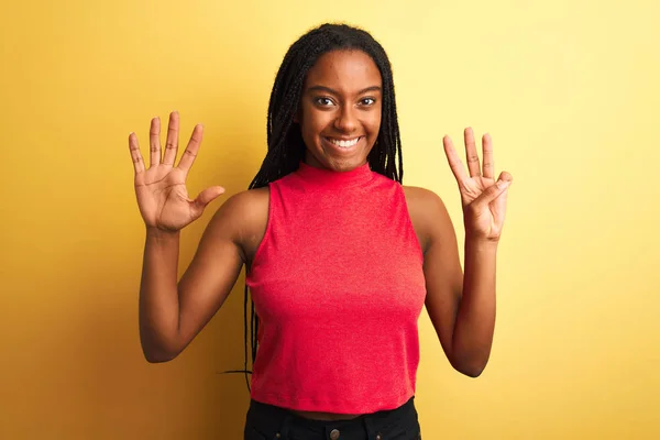 赤いカジュアルTシャツを着たアフリカ系アメリカ人女性が黄色の背景の上に立っていて 自信と幸せを笑顔で8番目の指で指しています — ストック写真