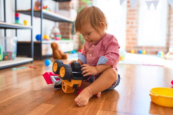 愛らしい幼児は 幼稚園のおもちゃの多くの周りにトラクターで遊んでいます — ストック写真