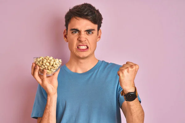 Adolescente Niño Sosteniendo Montón Pistachos Sobre Fondo Rosa Aislado Molesto — Foto de Stock