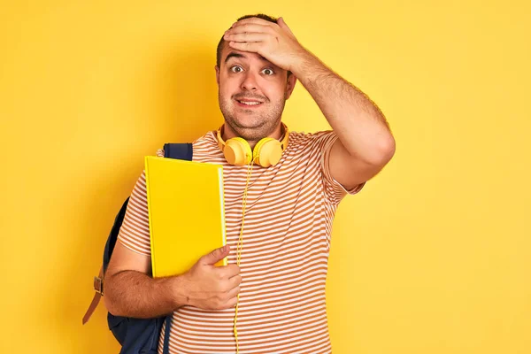 Student Noszący Słuchawki Plecakiem Trzymający Notatnik Odizolowanym Żółtym Tle Zestresowany — Zdjęcie stockowe
