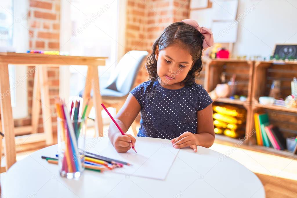 Beautiful toddler girl drawing cute draw using colored pencils at kindergarten