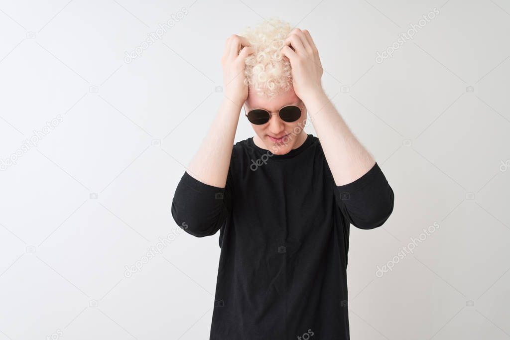 Young albino man wearing black t-shirt and sunglasess standing over isolated white background suffering from headache desperate and stressed because pain and migraine. Hands on head.