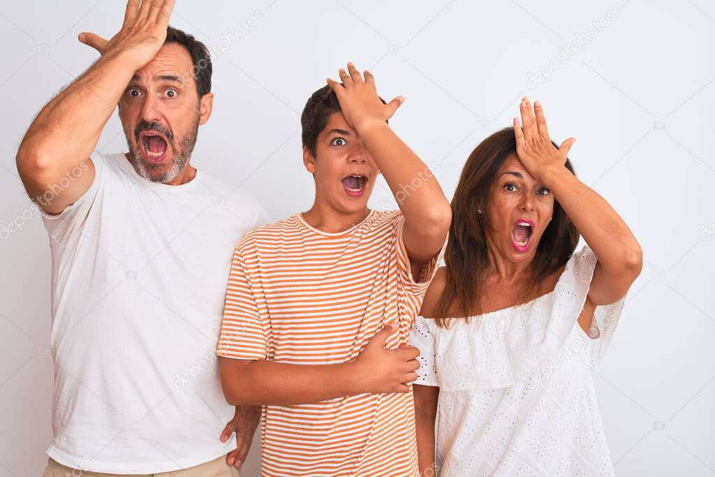 Family of three, mother, father and son standing over white isolated background surprised with hand on head for mistake, remember error. Forgot, bad memory concept.