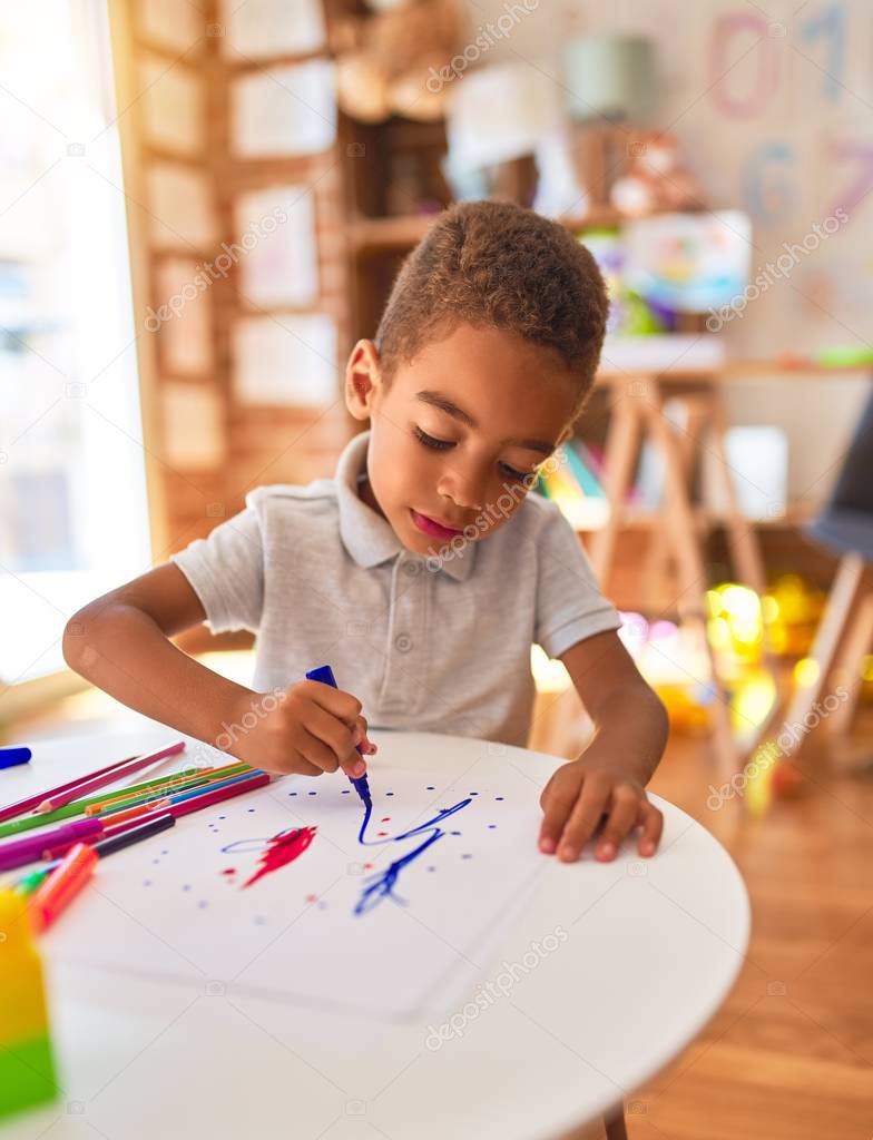 Beautiful african american toddler drawing using paper and marker pen at kindergarten