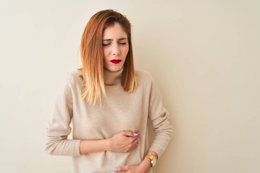 Kızıl saçlı kadın zarif bir balıkçı yaka kazak giyiyor ve midesi bulanan, acı verici bir hastalık yüzünden izole edilmiş beyaz arka planda duruyor. Ache kavramı.