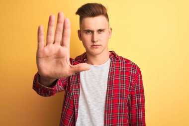 Sarı arka planda duran rahat tişörtlü genç ve yakışıklı bir adam avucunun içinde şarkı söylemeyi kesiyor. Yüzünde olumsuz ve ciddi bir jest olan uyarı ifadesi.