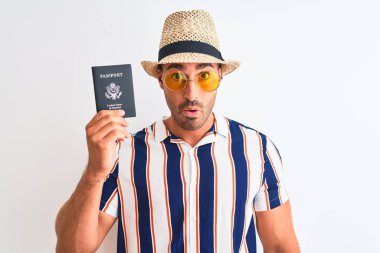 Yaz şapkası takan ve arka planda Usa pasaportu tutan genç turist şaşırmış bir yüzle korkmuş ve korku ifadesinden heyecanlanmış.